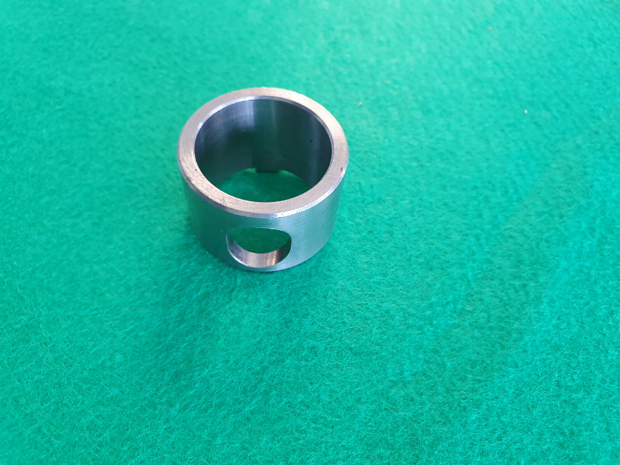 Una toma macro detallada de un componente industrial mecanizado de precisión hecho de acero de alta resistencia, mostrando un acabado superficial liso y pulido y tolerancias dimensionales extremadamente ajustadas. La superficie refleja la luz industrial ambiental, enfatizando su calidad impecable.
